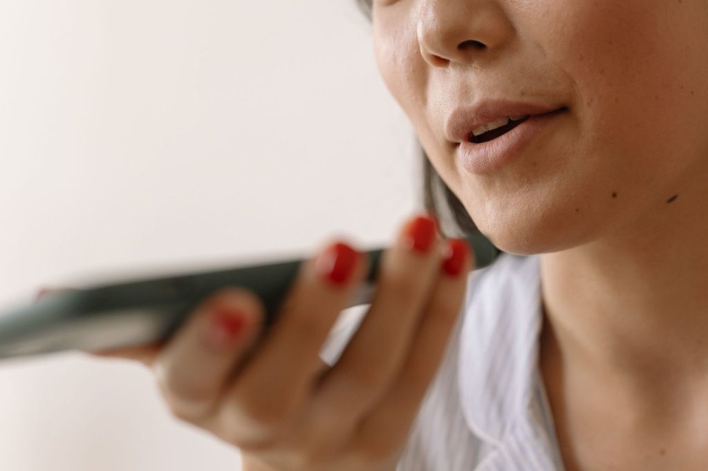 Mulher usa comando de voz no smartphone em um ambiente interno