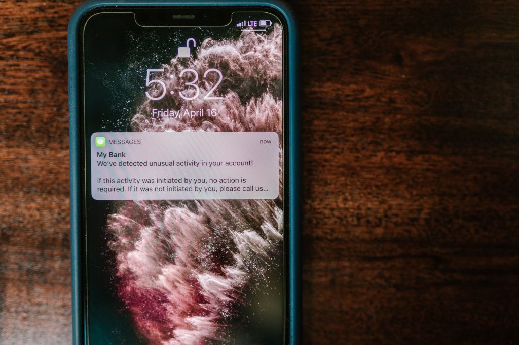 Governo cria comitê para fiscalizar bets após proibição nacional; veja cronograma de bloqueio Close de um smartphone sobre uma mesa de madeira exibindo uma notificação de alerta bancário.